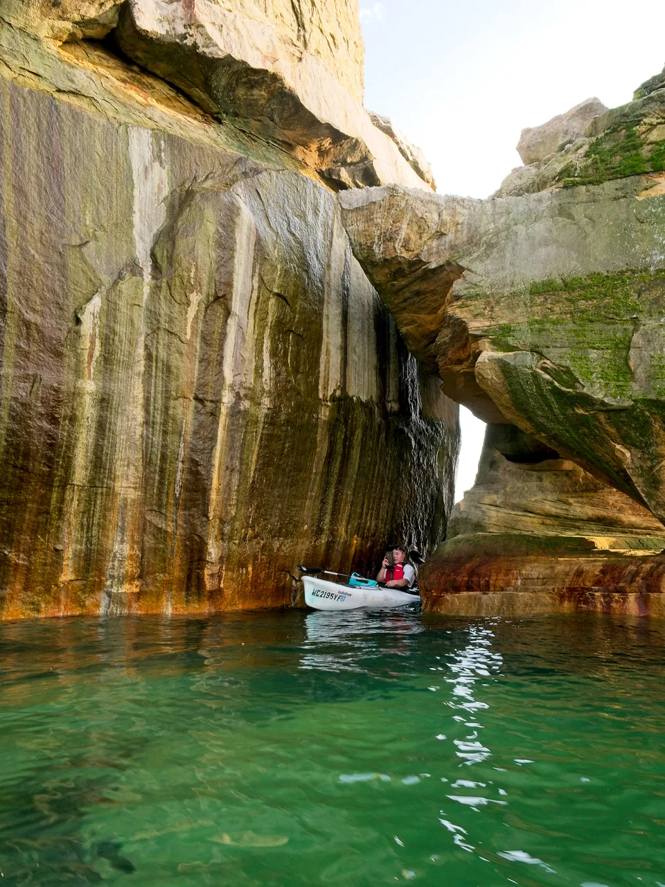 Still green water leads between mineral-streaked walls into a narrow rocky passage.