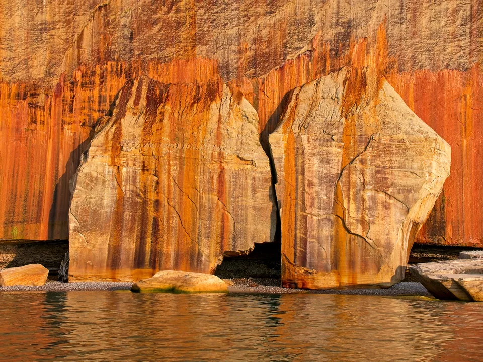 Evening light reveals a doorway carved through layers of iron-rich sandstone.